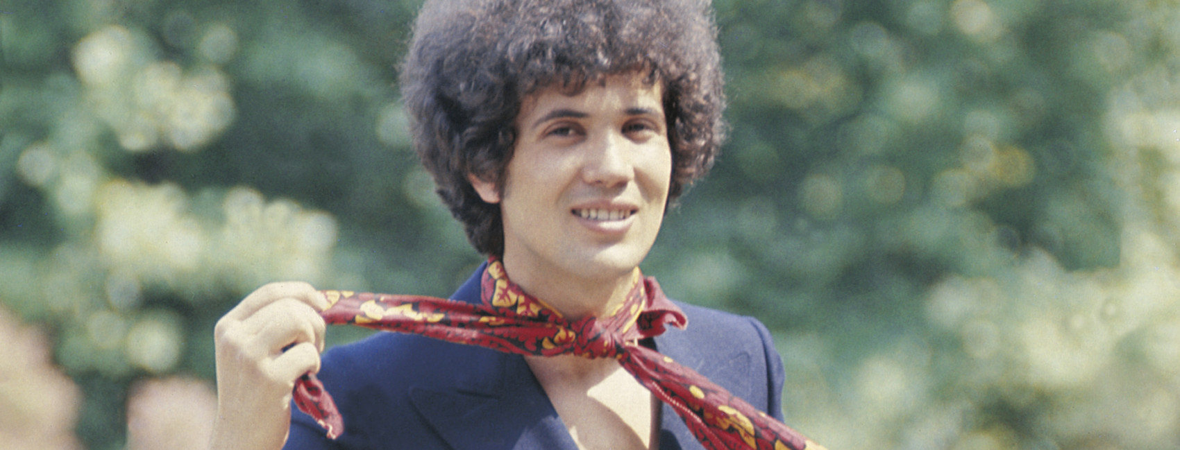 Il cantautore italiano Lucio Battisti si allaccia sorridente un foulard al collo. 1969